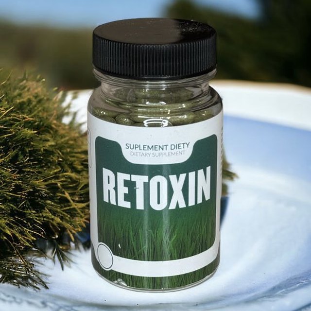 Retoxin — dóza se zelenými kapslemi na zahradě, etiketa s trávou a nápisem Retoxin