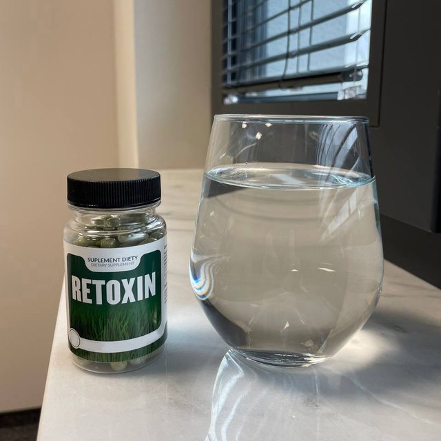 Retoxin — słoik z zielonymi kapsułkami trzymany w dłoni, etykieta z trawą i napisem Retoxin